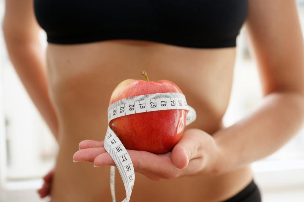 foto de abdomen con metro de medida y manzana